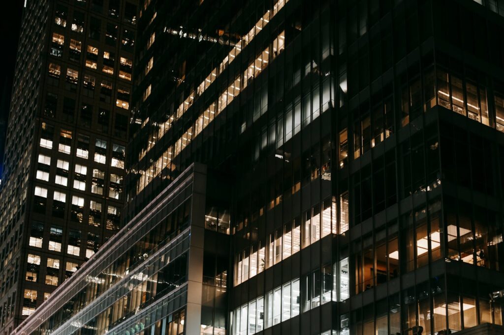 Illuminated skyscrapers in a vibrant city at night, showcasing modern architecture and urban life.